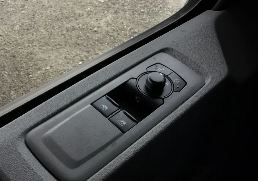 Commande des rétroviseurs et des vitres côté conducteur du Volkswagen Transporter T7 gris stone, vue en plongée.