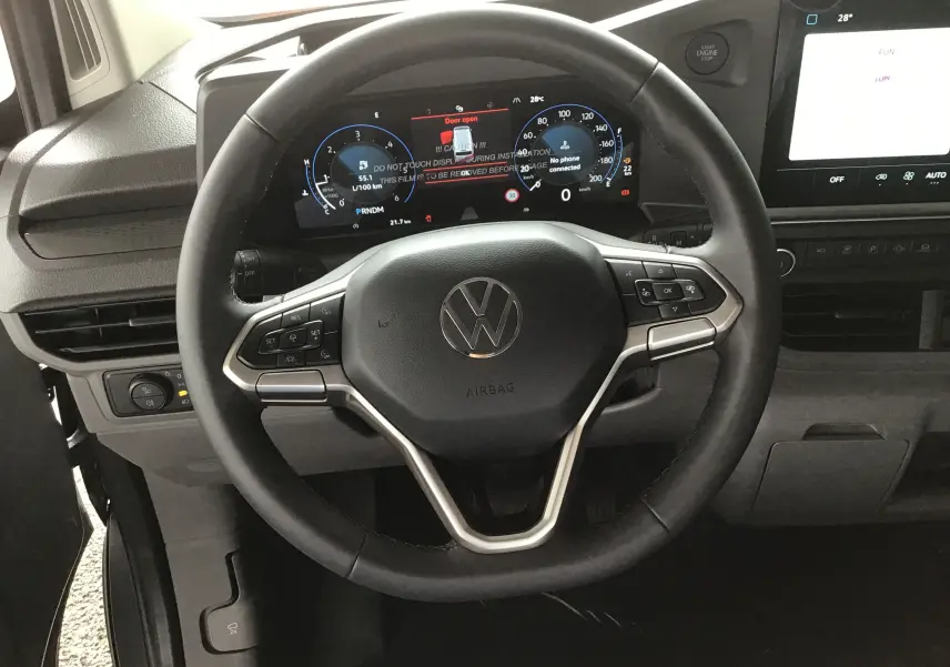 Vue rapprochée du volant et du tableau de bord numérique du Volkswagen Transporter T7, ambiance intérieure moderne et fonctionnelle.