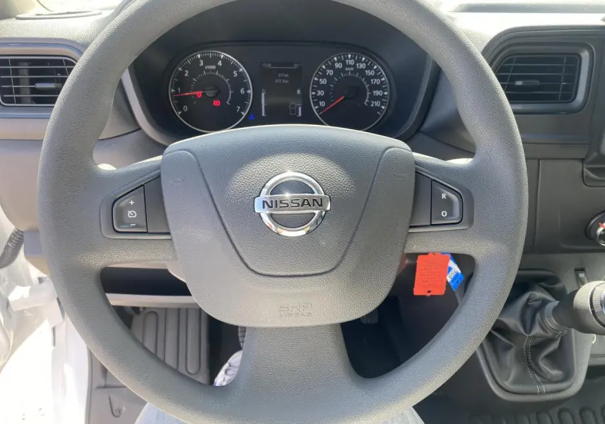 Vue centrée sur le volant Nissan du tableau de bord du fourgon blanc Interstar, avec commandes au volant et levier de vitesse manuel.