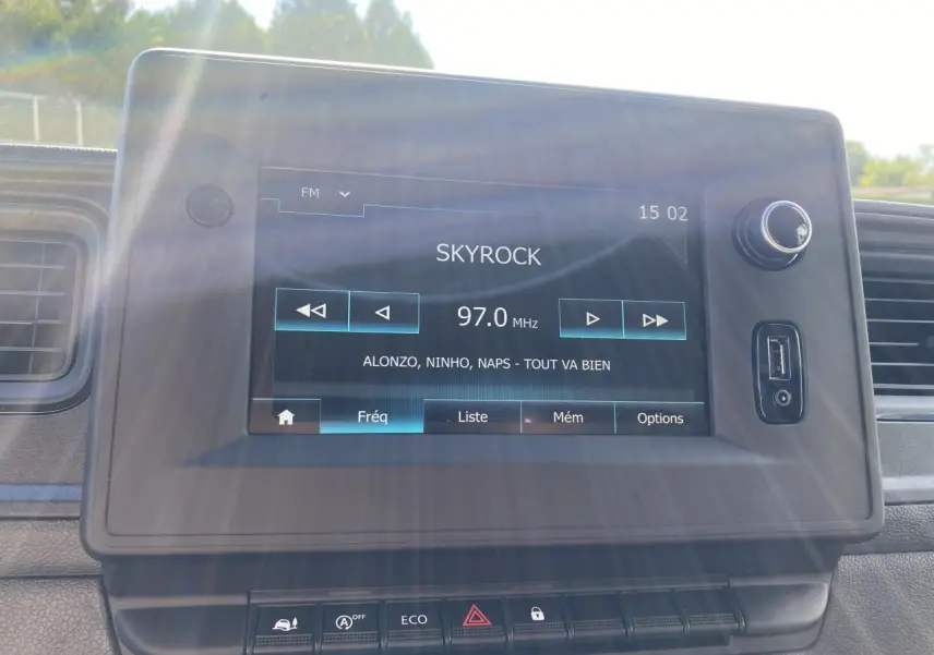 Écran tactile du système NissanConnect affichant la radio FM sur un tableau de bord noir du Nissan Interstar blanc 2022.