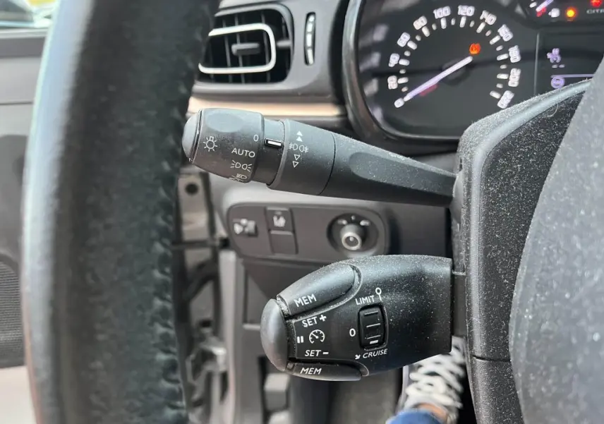 Gros plan sur les commandes de régulateur et feux du tableau de bord d'une Citroën C3 gris foncé de 2019.