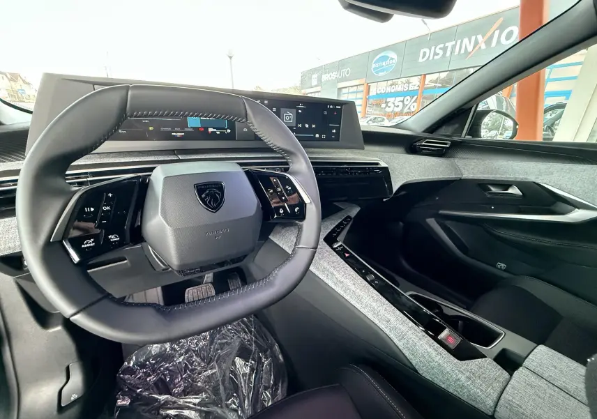 Intérieur du Peugeot 3008 Hybrid 2025 vu côté conducteur, volant compact et tableau de bord numérique moderne.