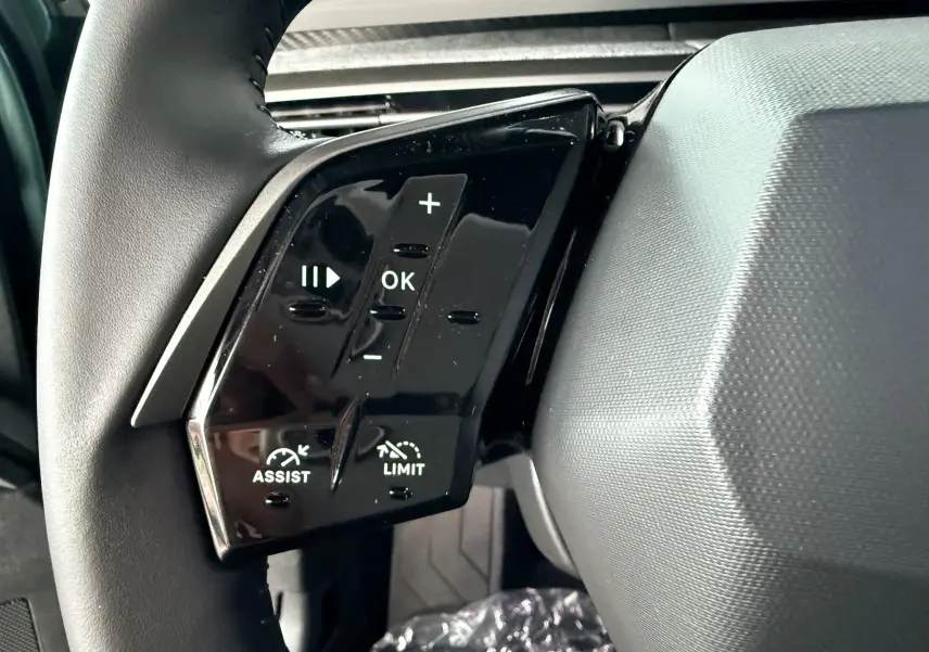 Gros plan sur les commandes au volant gauche du Peugeot 3008 Hybrid 2025 avec boutons de réglage et limitation de vitesse.