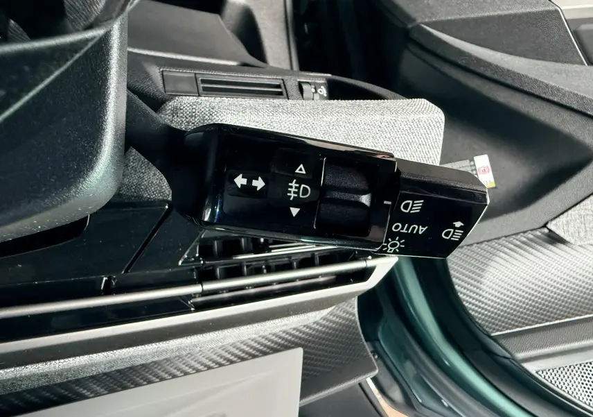 Gros plan sur la commande des phares et clignotants du Peugeot 3008 Hybrid 2025, intérieur gris et bleu Ingaro Metal visible.