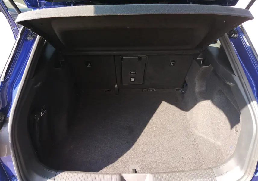 Coffre ouvert vu de l'arrière d'un Volkswagen ID.4 bleu métal, montrant un espace de chargement propre et spacieux.