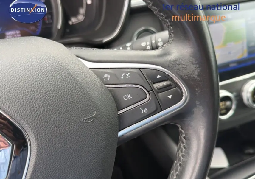 Gros plan sur le volant en cuir noir du Renault Kadjar 2021, avec commandes intégrées et tableau de bord flou en arrière-plan.