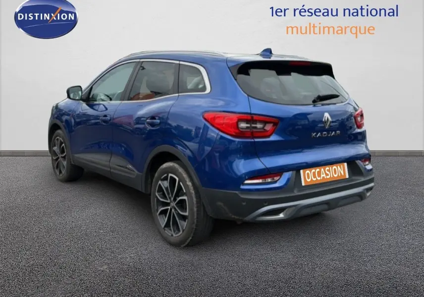 Vue 3/4 arrière droite du Renault Kadjar bleu Iron avec jantes alliage et logo visible sur un fond neutre.