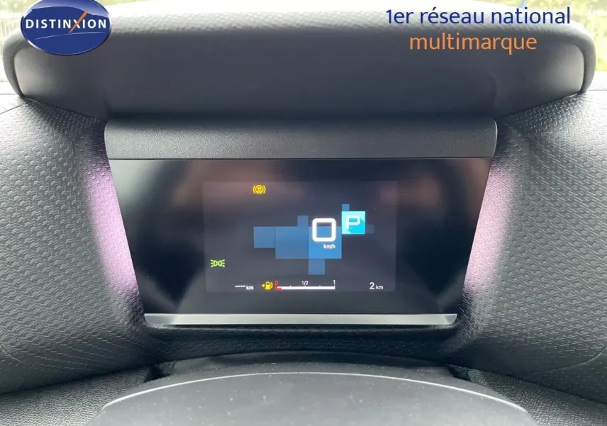 Écran numérique du tableau de bord de la Citroën C4 blanche, affichant la vitesse à 0 km/h et le mode parking activé.
