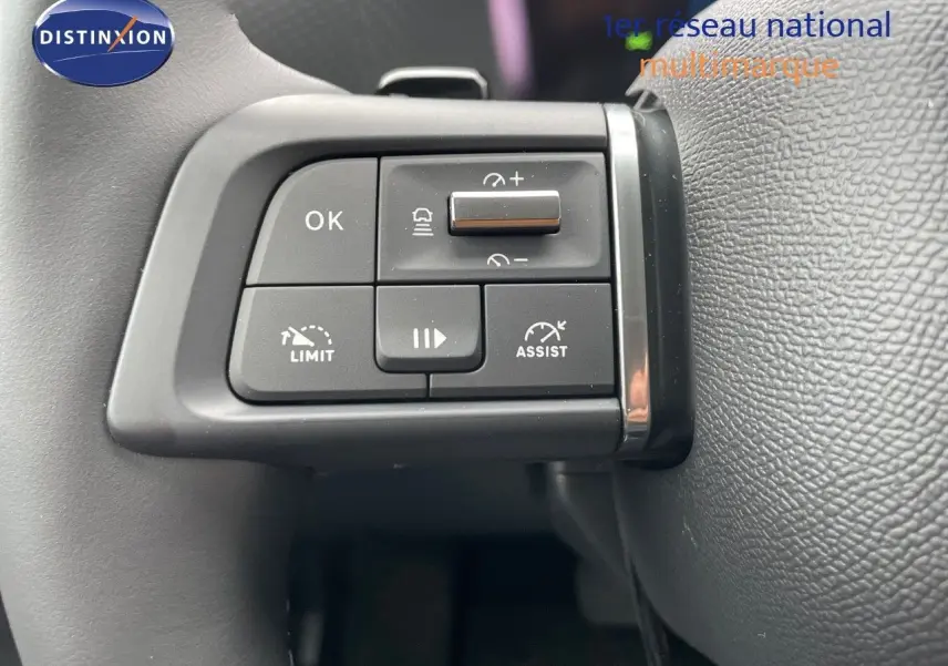 Gros plan sur les commandes au volant à gauche d'une Citroën C4 blanche métal 2024, version essence automatique.