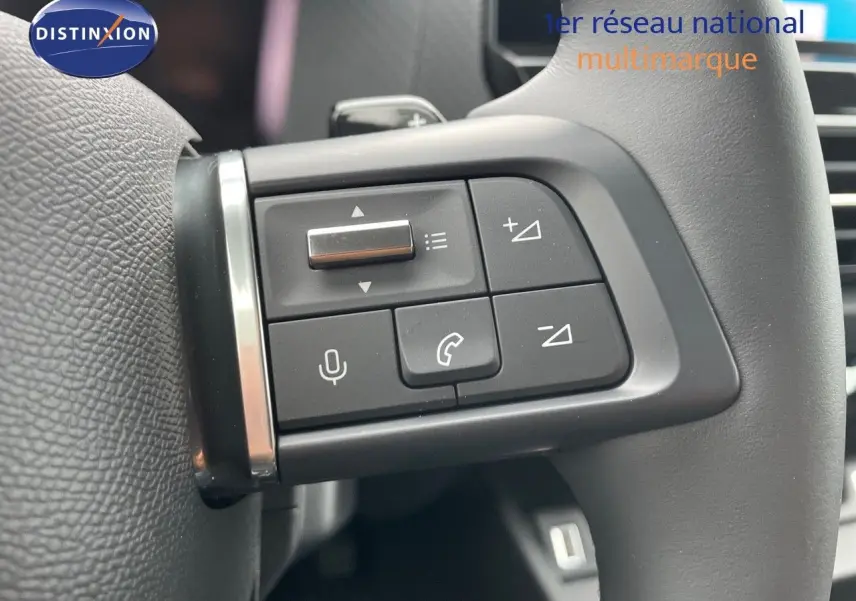 Gros plan sur les commandes vocales et téléphone intégrées au volant d'une Citroën C4 blanche 2024.