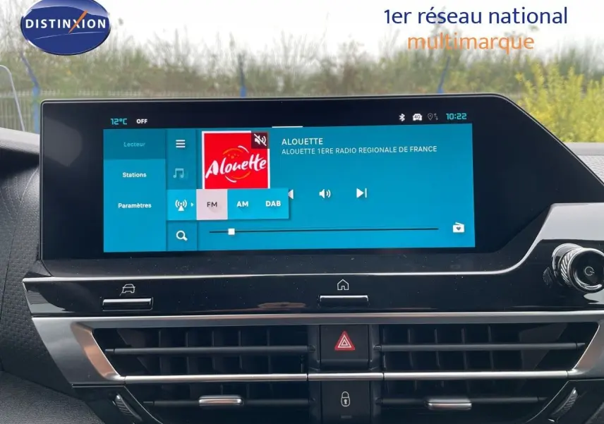 Écran tactile central allumé dans l'habitacle du Citroën C4 blanc métal, affichant une radio FM.