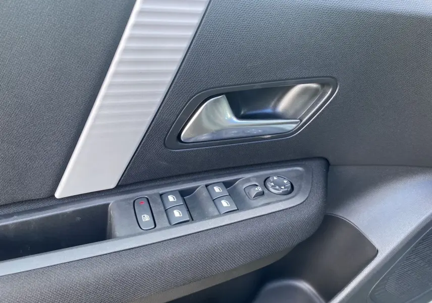 Détail de la porte côté gauche de la Citroën C4 Manhattan Green 2025 avec commandes de vitres et poignée argentée.