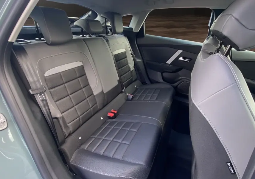 Vue intérieure arrière droite des sièges en tissu noir et gris de la Citroën C4 Nouvelle Plus Hybrid 2025 Manhattan Green.