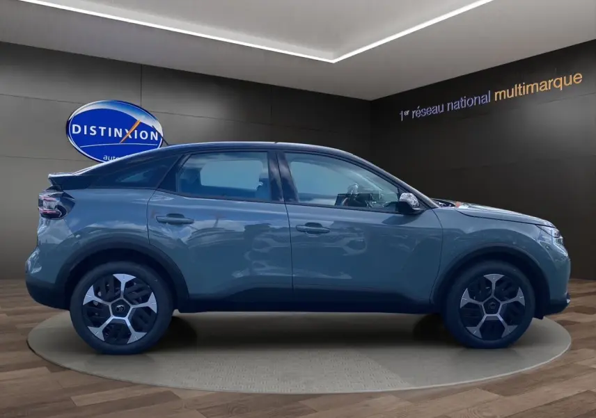 Profil droit de la Citroën C4 2025 Manhattan Green avec toit noir et jantes stylisées en showroom.