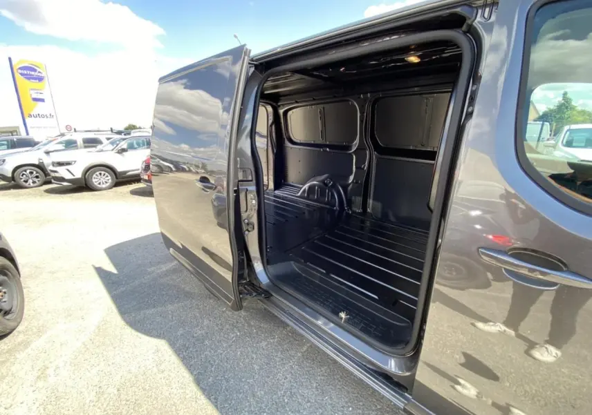Vue latérale droite d'un Peugeot Expert Fourgon gris platinium avec porte coulissante ouverte montrant l'espace de chargement vide.