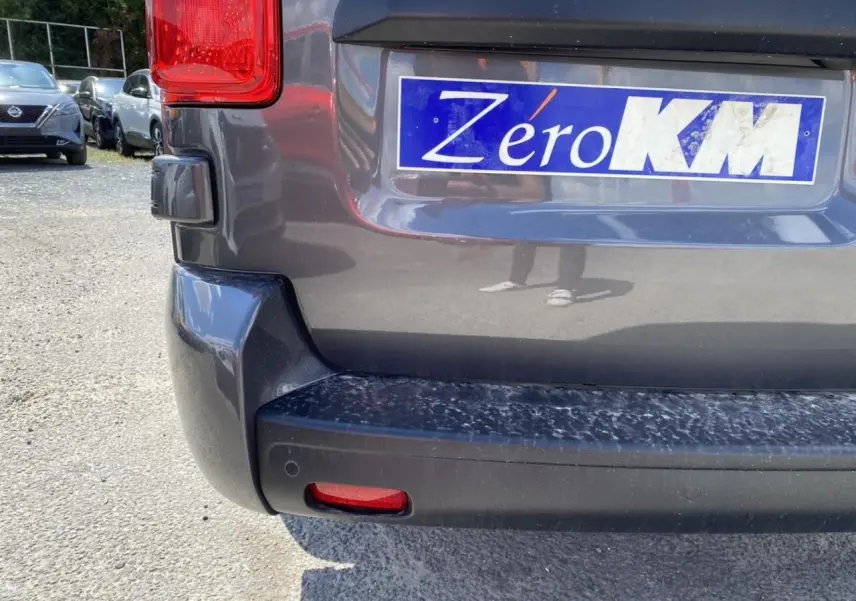 Gros plan sur le pare-chocs arrière gris platinium du Peugeot Expert Fourgon avec plaque Zéro KM visible.