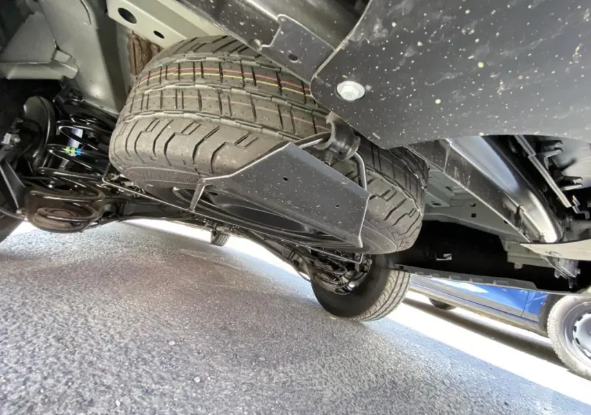 Vue en contre-plongée sous un Peugeot Expert Fourgon gris platinium, montrant la roue de secours sous le châssis.