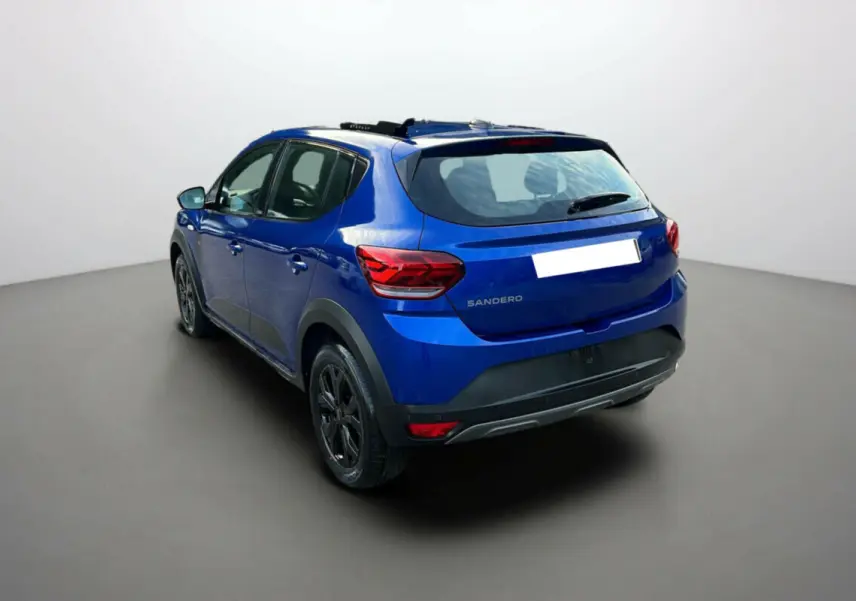 Vue 3/4 arrière d'une Dacia Sandero Stepway 2024 bleu iron avec jantes noires et protections noires sur les passages de roues.