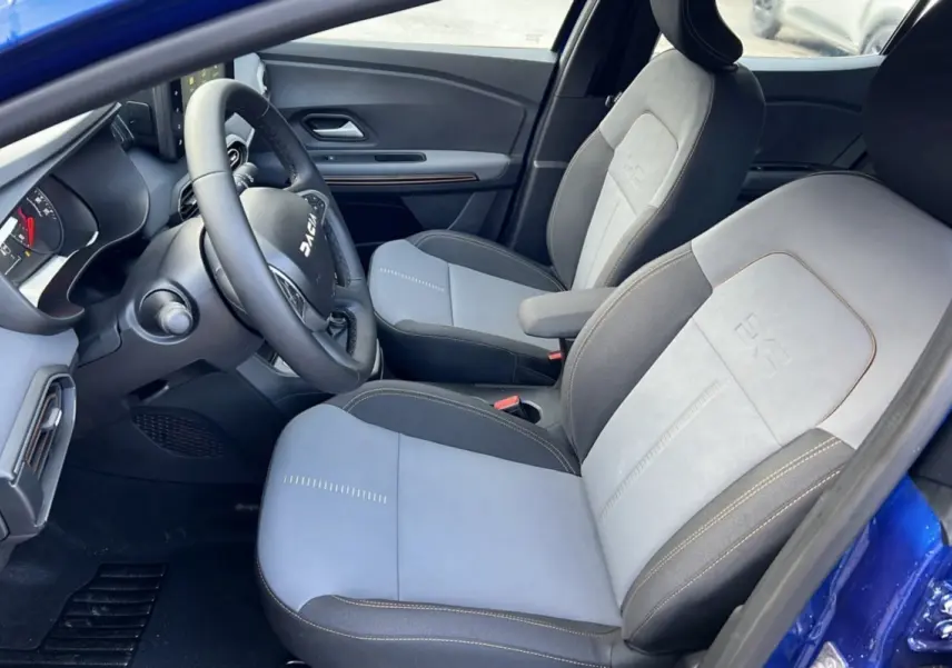 Intérieur de la Dacia Sandero Stepway 2024 en bleu iron, vue côté conducteur avec sièges bi-matière gris clair et foncé.