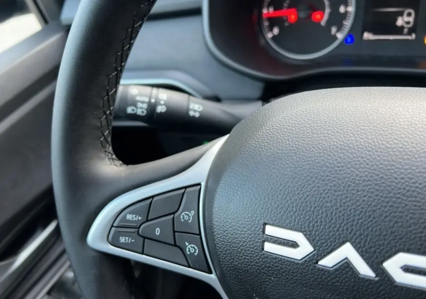 Gros plan sur le volant noir de la Dacia Sandero Stepway 2024, avec commandes de régulateur de vitesse visibles.