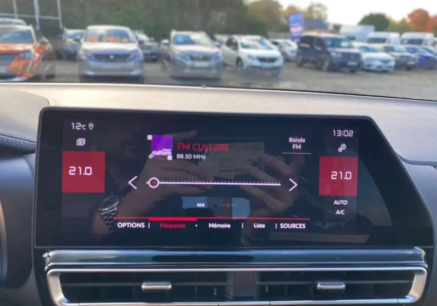 Écran tactile central du tableau de bord du Citroën C5 Aircross 2025 affichant la radio FM et la climatisation à 21°C.