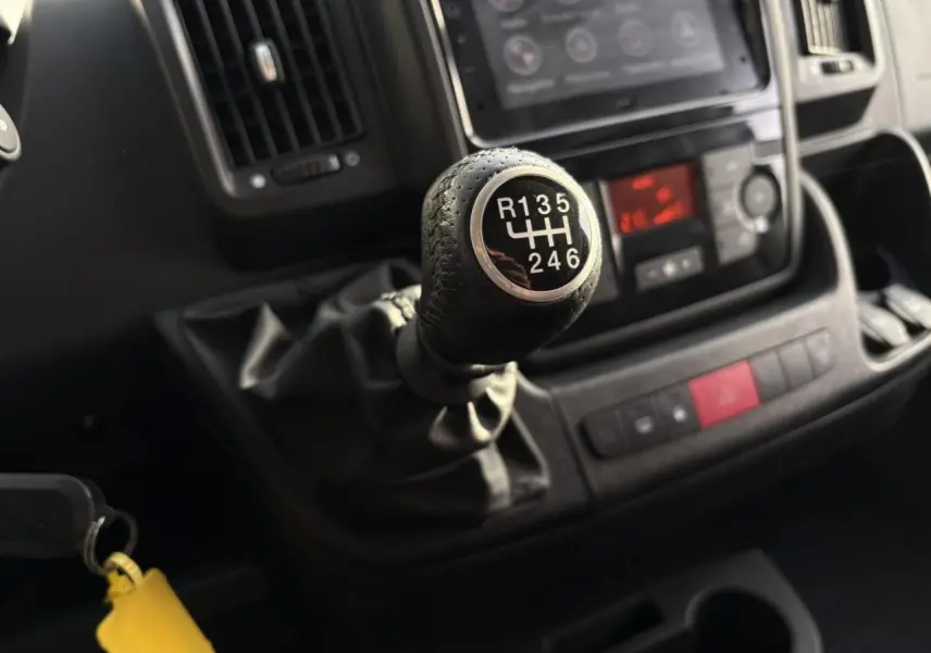 Gros plan sur le levier de vitesses manuel noir dans l’habitacle sombre de l’Opel Movano Fourgon blanc 2024.