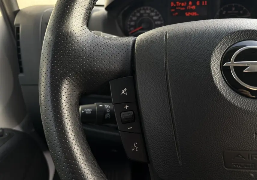 Gros plan sur le volant noir perforé d’un Opel Movano Fourgon 2024 avec commandes audio intégrées.