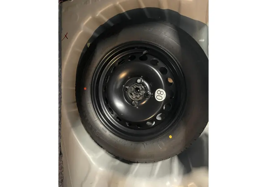 Gros plan sur la roue de secours noire du Dacia Sandero Stepway blanc glacier 2025, vue de dessus dans le coffre.