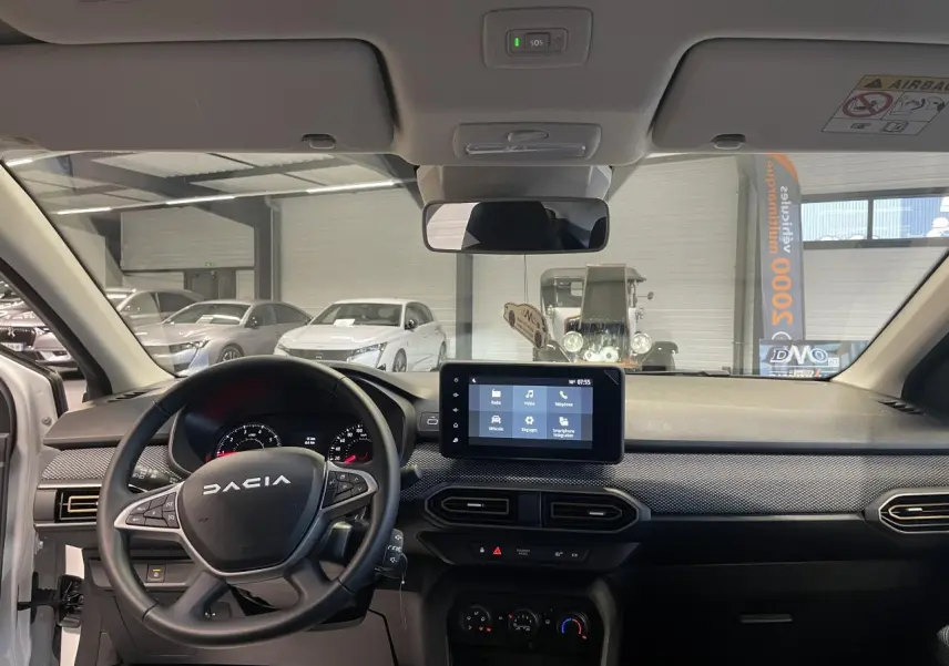 Vue intérieure avant du tableau de bord de la Dacia Sandero TCe 90 Stepway blanc glacier avec écran tactile et volant multifonction.