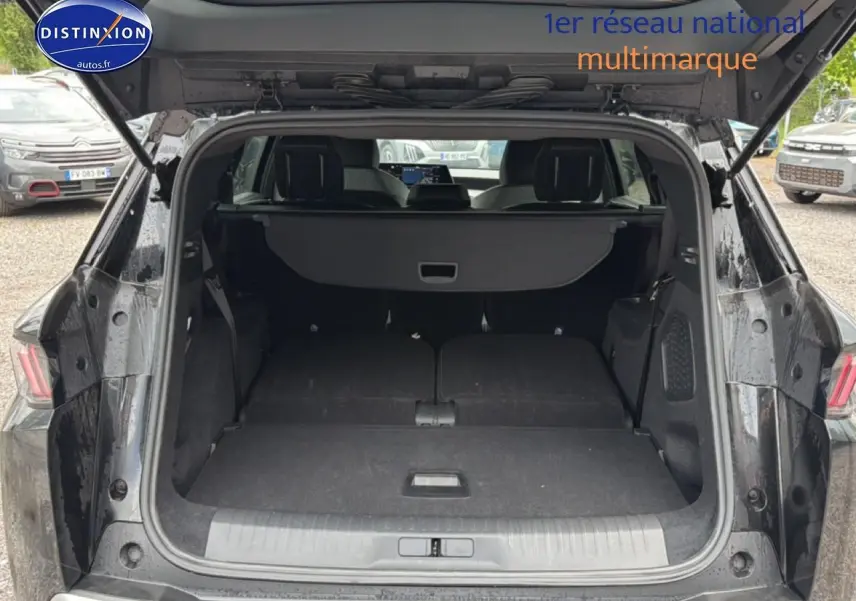 Coffre ouvert d’un Peugeot 5008 noir vu de l’arrière, banquette arrière rabattue pour un grand espace de chargement.