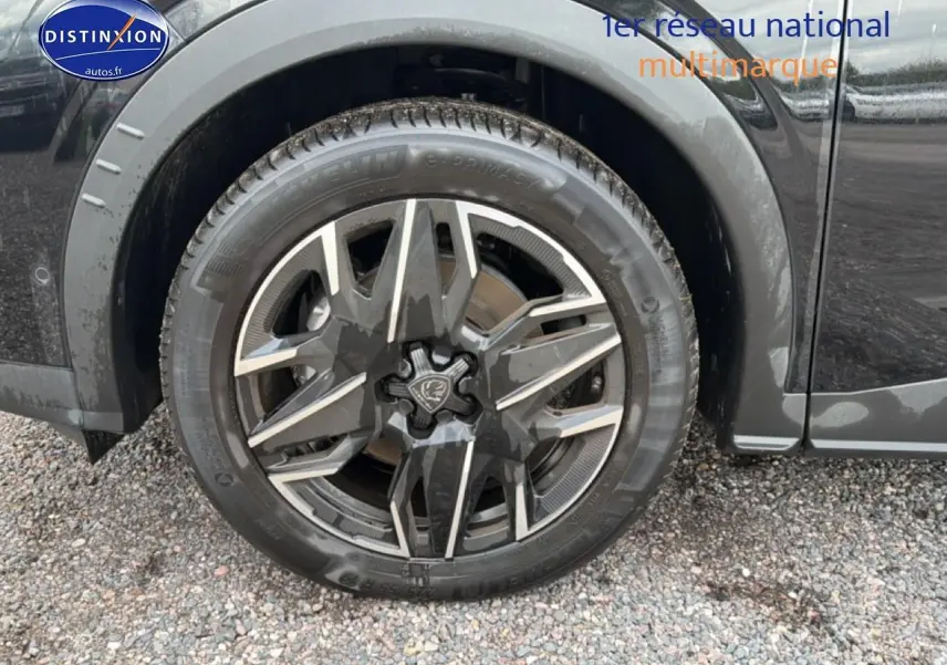 Gros plan sur la roue avant gauche noire du Peugeot 5008 Hybrid 145 allure e-dcs6 avec jante alu design.
