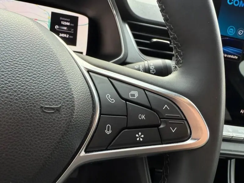 Gros plan sur les commandes au volant du Renault Captur 2025, finition Techno, avec cuir noir et surpiqûres visibles.