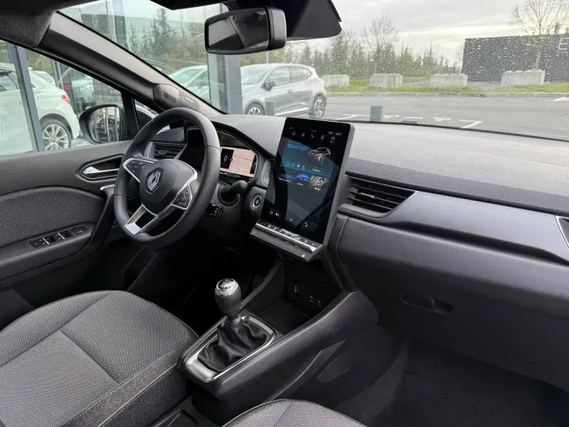 Vue intérieure côté conducteur du Renault Captur 2025, tableau de bord moderne avec écran tactile vertical et boîte manuelle.