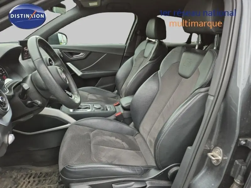 Vue intérieure côté conducteur de l'Audi Q2 1.4 TFSI S line 2017 avec sièges sport noirs et volant cuir multifonction.