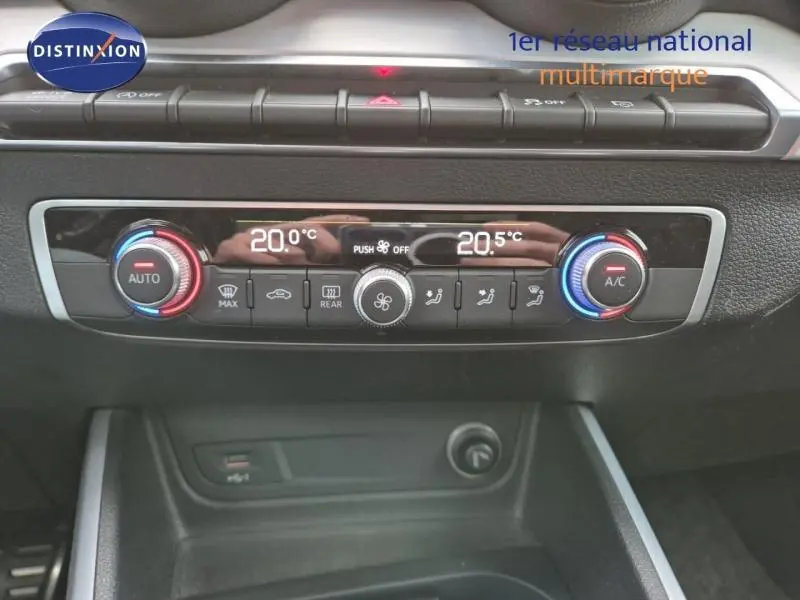 Gros plan sur la console de climatisation automatique bi-zone de l'Audi Q2 avec réglages numériques et boutons noirs.