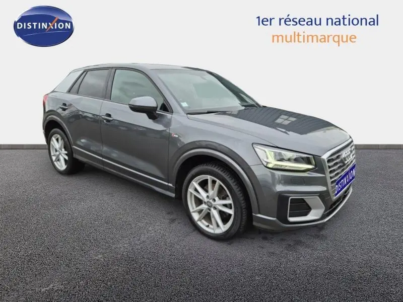 Audi Q2 gris Manhattan en 3/4 avant droit, avec jantes alu et signature lumineuse LED distinctive.