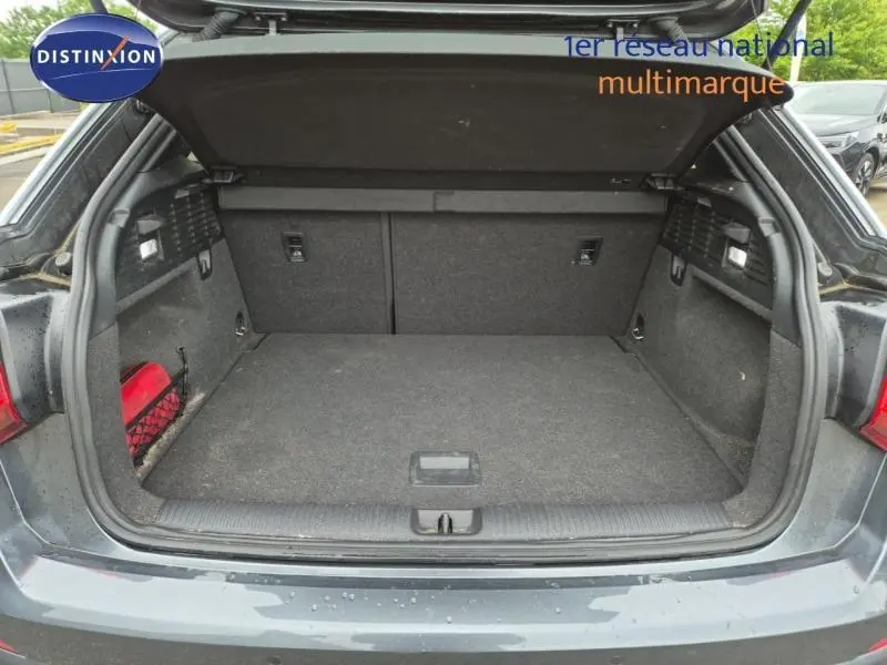 Coffre ouvert vu de l'arrière d'un Audi Q2 gris Manhattan, espace de chargement vide et tapis gris.
