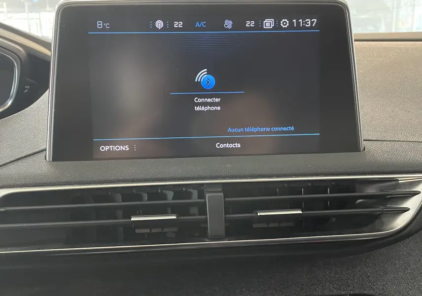 Écran tactile central du tableau de bord du Peugeot 5008 blanc nacré, affichant la connexion Bluetooth et la climatisation.