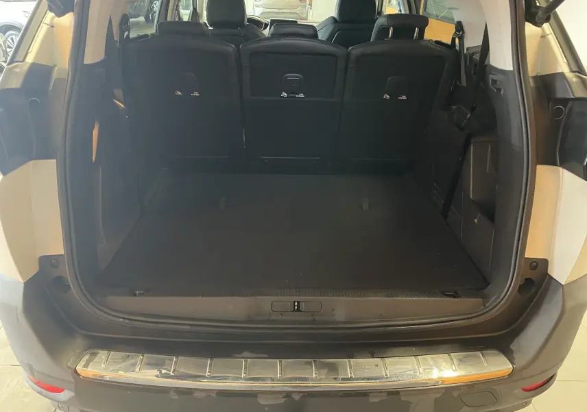 Coffre ouvert du Peugeot 5008 blanc nacré, vue arrière montrant l'espace de chargement et les sièges arrière noirs.
