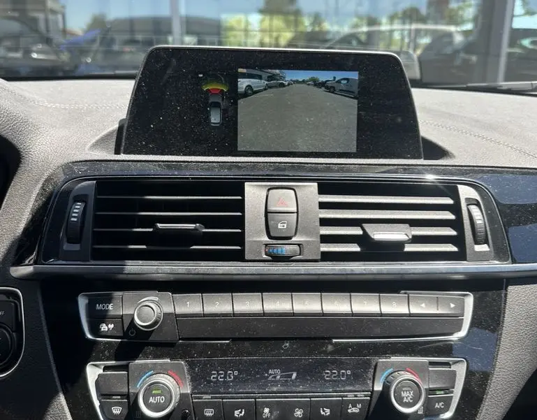 Vue rapprochée de la console centrale d'une BMW Série 1 F20 gris foncé, avec écran multimédia affichant la caméra de recul.