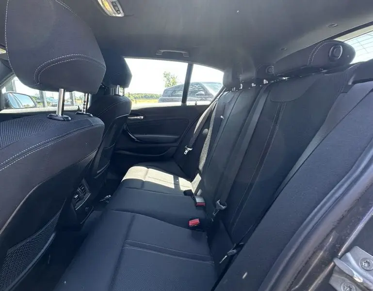 Vue intérieure arrière de la BMW Série 1 F20 116D 2019, sièges arrière en tissu noir avec surpiqûres blanches.