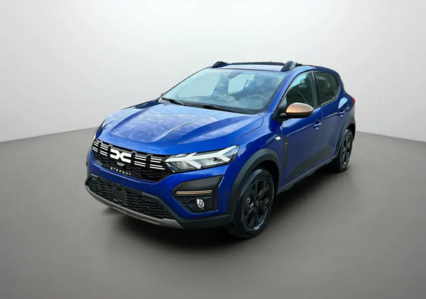 Dacia Sandero Stepway 2024 bleu iron en 3/4 avant droit avec coques de rétroviseurs bronze et jantes noires.