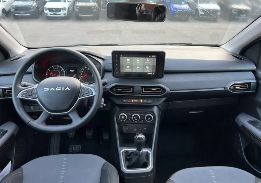 Vue intérieure avant du tableau de bord et volant Dacia Sandero Stepway Bleu iron avec boîte manuelle et écran tactile central.