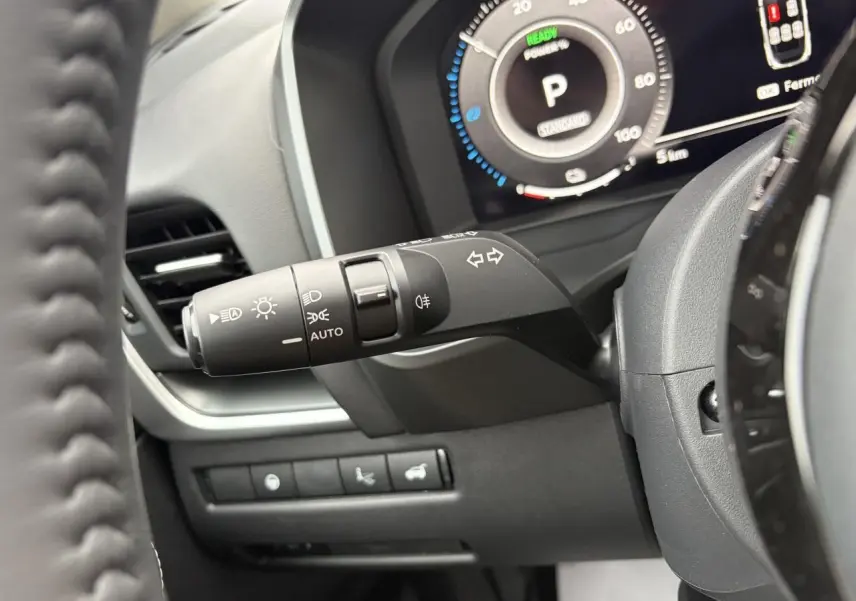Gros plan sur la manette de clignotants et tableau de bord numérique du Nissan Qashqai 2025, intérieur noir.