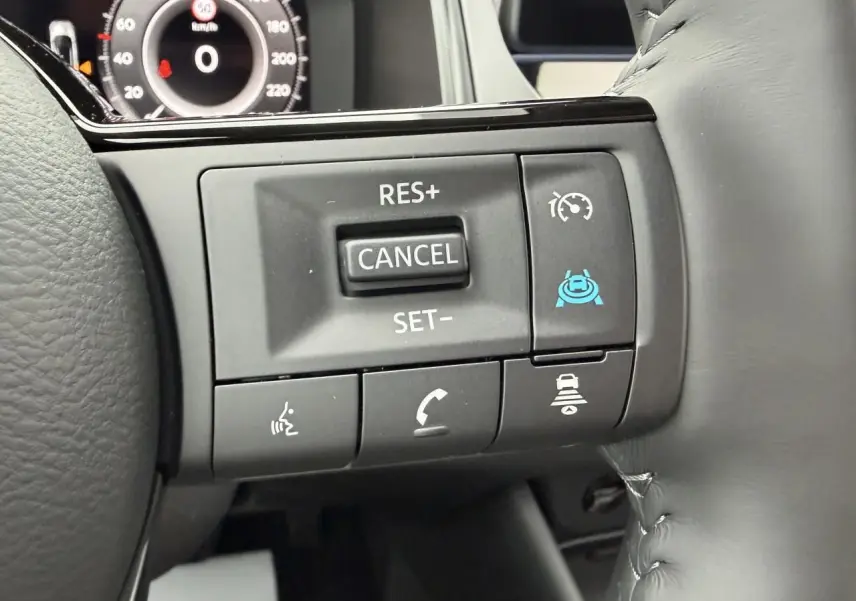 Gros plan sur les commandes du volant à droite du Nissan Qashqai 2025, boutons de régulateur et assistant de conduite visibles.