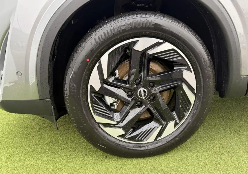 Gros plan sur la roue avant droite du Nissan Qashqai 2025 gris foncé avec jante alliage noire et argentée design moderne.