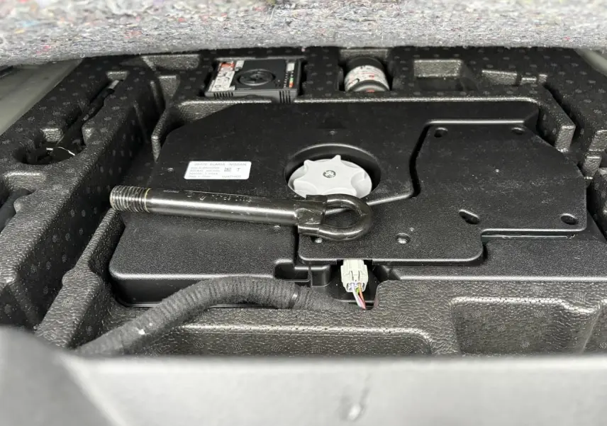 Gros plan sur le coffre ouvert du Nissan Qashqai 2025, montrant le rangement d'outils et l'équipement de bord.