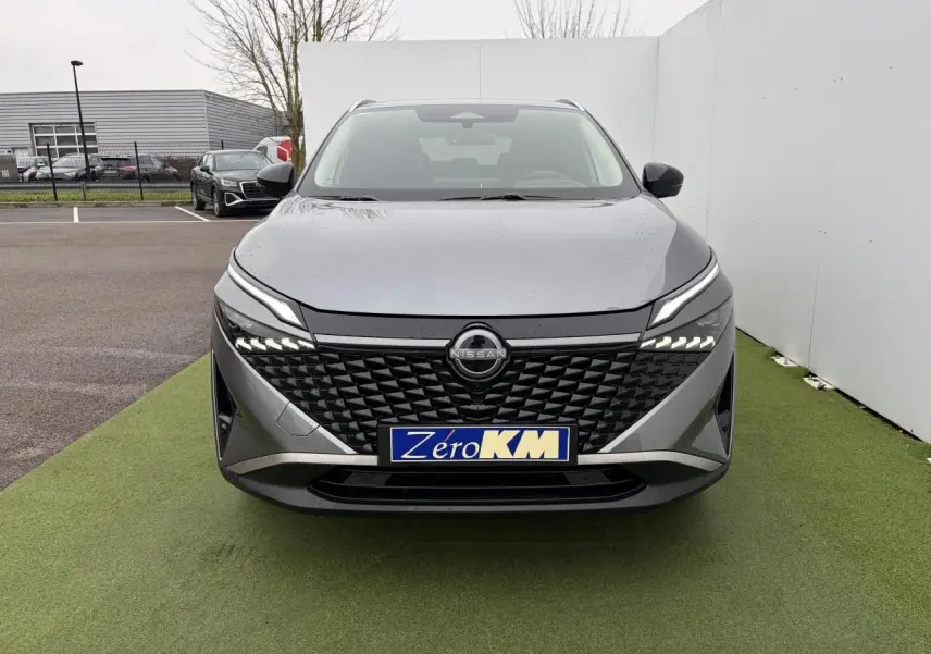 Vue frontale du Nissan Qashqai III 1.5 Hybrid E-Power gris foncé avec calandre noire et feux LED allumés.