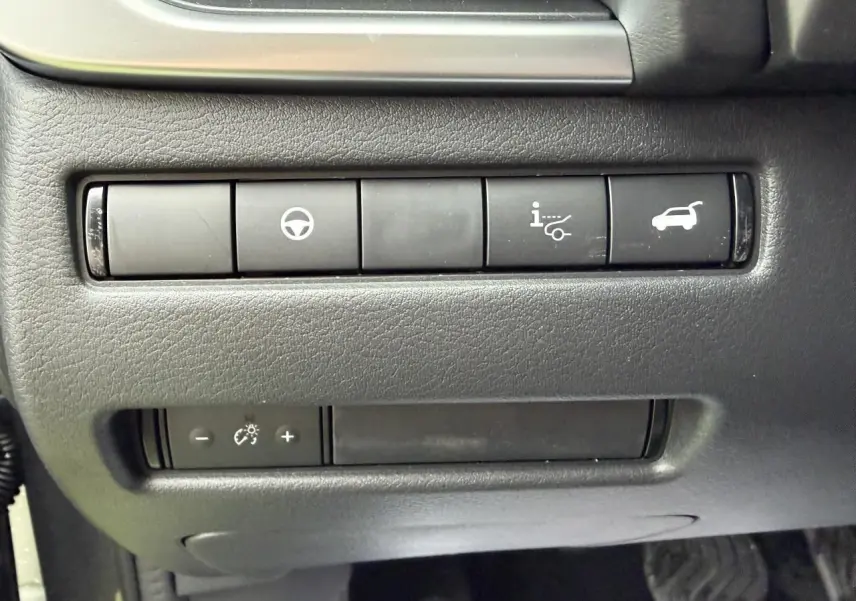 Gros plan sur les boutons de commande noirs du tableau de bord du Nissan Qashqai III gris foncé, côté conducteur.