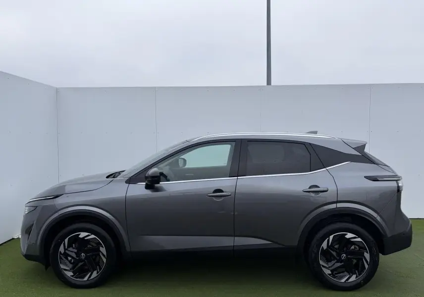 Profil droit du Nissan Qashqai III 1.5 Hybrid E-Power 2025 en gris métallisé avec jantes alliage noires et toit contrasté.